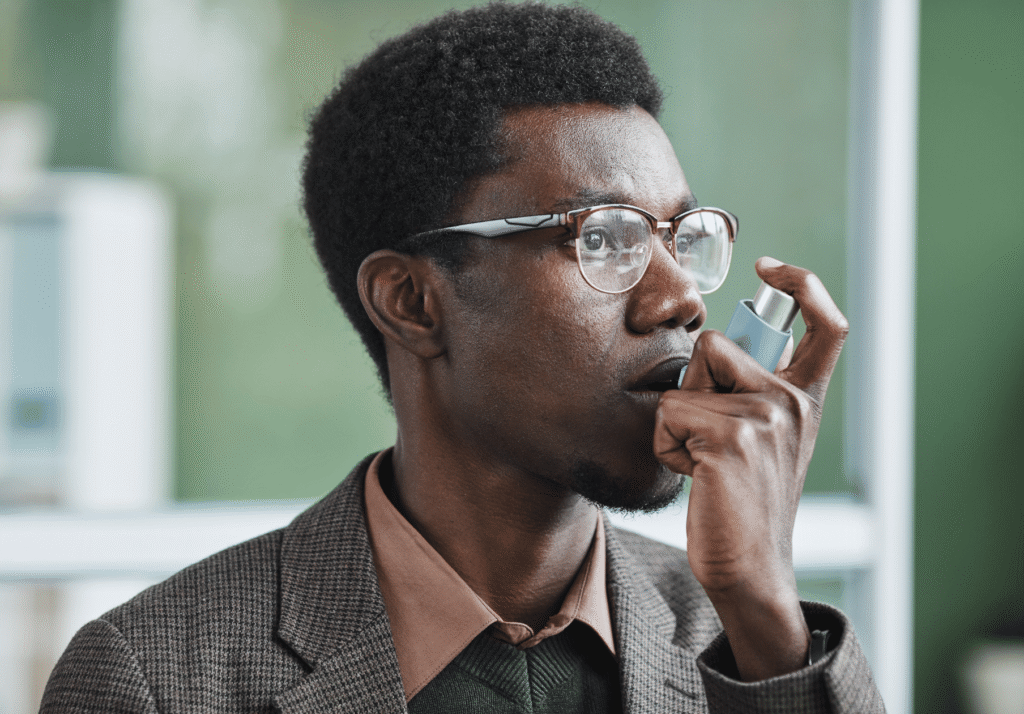African young businessman using inhaler during work at office he has asthma | Pharmarun